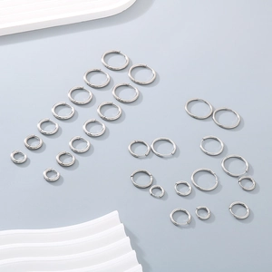 Set of minimalist silver titanium steel hoop earrings on a decorative white display