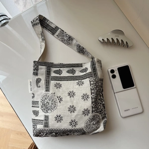 Detail view of cotton linen shoulder bag with black paisley patterns and brand label