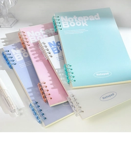 Stack of pastel B5 spiral notebooks in light blue, pink, and grey on white background