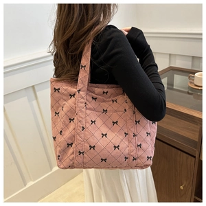 Detail of pink corduroy tote bag with diamond quilting and black bow print texture