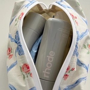 Close-up of floral bow cosmetic bag showing spacious interior with skincare bottles