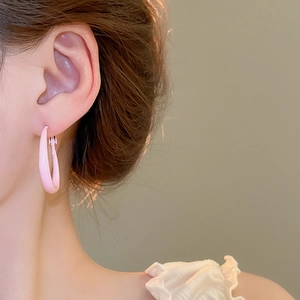 Close-up of a model wearing smooth pink U-shaped oval hoop earrings for a stylish look