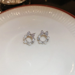 Elegant silver-toned bow wreath earrings with small pearls and clear zircon in a white dish