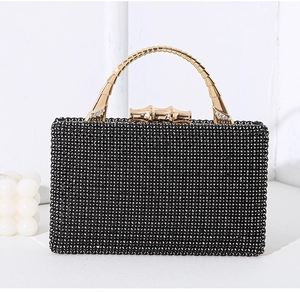 Close-up of black rhinestone evening clutch with elegant gold bamboo metal handle