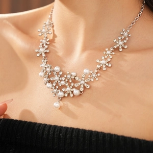 Detailed close-up of a silver flower necklace featuring faux pearls and crystals on a model