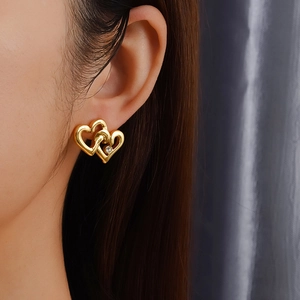 Close-up of heart-shaped gold stud earring with zircon inlay worn by a female model