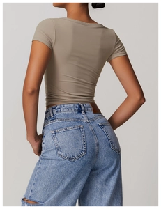 Close-up of fitted taupe short-sleeve shirt with V-neck pleated hem and denim jeans back detail