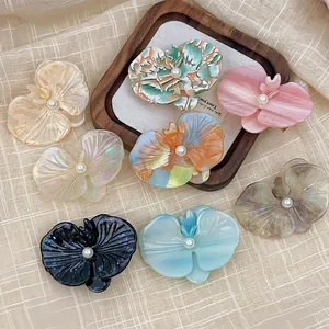 Detailed set of acetate orchid flower hair clips with pearls on a textured background