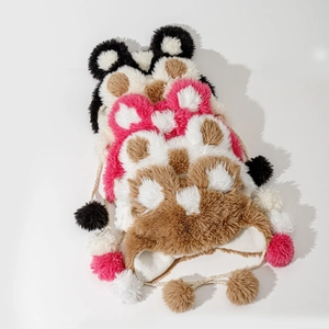Detailed view of plush animal ear hats with braided ropes and large fluffy pom-poms