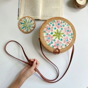 Detail of round straw crossbody bag with colorful shell flower inlay and leather strap