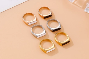 Close-up of minimalist stainless steel signet rings in gold, silver, and rose gold finishes