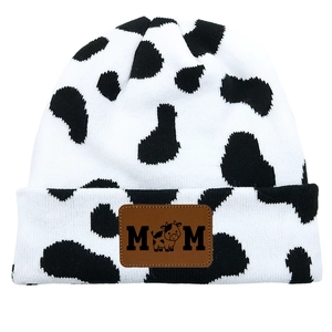 Detail of cow print knitted beanie with vintage brown leather MOM patch and calf icon