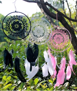Outdoor detail of black, white and pink dreamcatchers with goose feathers and beads