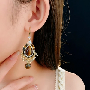 Close-up of vintage gold drop earrings with brown tiger eye stone and crystal fringe