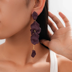Close-up of purple petal tassel earrings with gold chain link on a female model