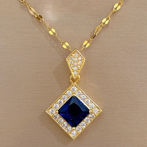 Close-up of golden necklace with blue diamond-shaped gemstone and micro-paved crystals