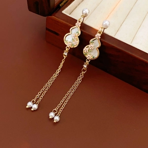 Detail of golden gourd flower earrings with white inlay and elegant tassel pearls