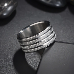 Detail of silver matte ring with four frosted decorative bands on dark stone base