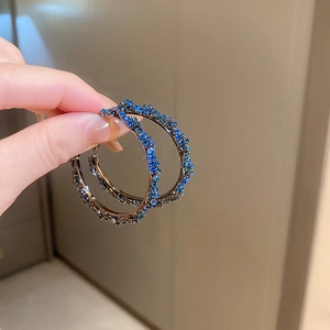 Detailed close-up of gunmetal twist hoop earrings with dark blue pavé rhinestones