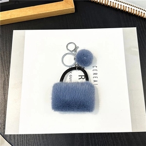 Close-up of blue plush handbag keychain with metal ring and fluffy pompom detail