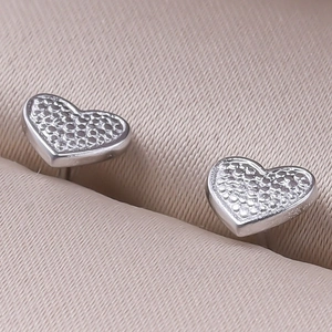 Macro shot of silver heart-shaped stud earrings with unique grainy metal texture details