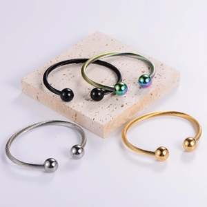 Close-up of four colored braided wire cuff bracelets with spherical ends on stone