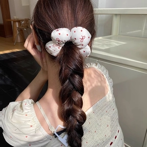 White floral hair scrunchie with red heart print worn on a ponytail by a model