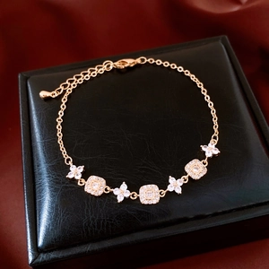 Détail d'un bracelet fleur plaqué or 18 carats avec zircons sur une boîte en cuir noir