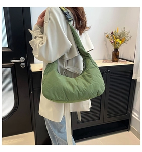 Gros plan sur un sac matelassé vert herbe avec sangle réglable porté par le mannequin