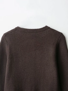 Détail du cardigan en maille marron foncé montrant les coutures fines du col et de l'épaule