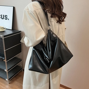 Grand sac fourre-tout noir minimaliste en cuir souple porté à l'épaule par le mannequin