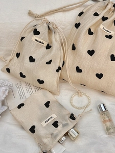 Three sizes of champagne satin drawstring pouches with heart prints for storage