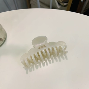 Close-up of wavy cloud acetate hair claw clip in creamy white with glossy finish