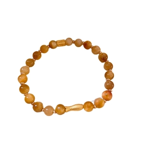 Bracelet en perles œil de tigre avec breloque poisson dorée vintage sur fond blanc pur