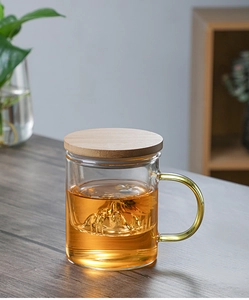 Detail of glass tea cup with mountain base design, wooden lid and floating chrysanthemum