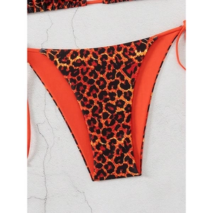 Detail of orange leopard print bikini bottom with side ties on a textured stone surface
