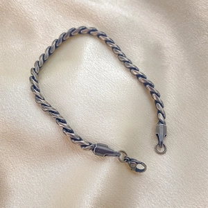Dettaglio macro del bracciale a catena ritorta in acciaio inox su raso