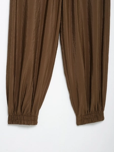 Close-up of elastic cuffs on brown safari trousers with subtle satin fabric texture