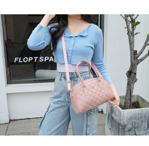 Détail du sac à main matelassé rose avec logo floral doré et bandoulière amovible