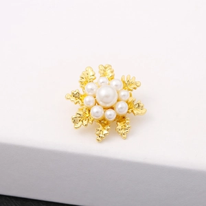 Detailed macro shot of a golden snowflake brooch with elegant pearl inlays and metal luster