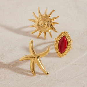 Detailed set of gold sun, starfish, and red agate rings on a warm textured surface
