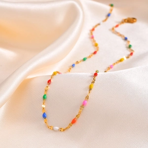 Golden stainless steel necklace with vibrant colorful enamel beads on silk background