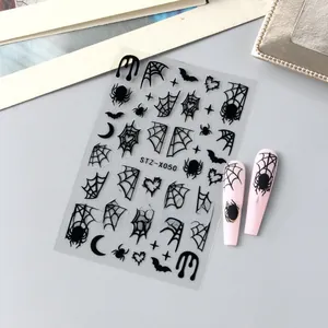 Detail of Halloween nail stickers with black spiders, webs, and bats on pink matte nails