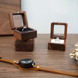 Detail of walnut wood ring boxes with glass windows and magnetic lids on a wooden surface