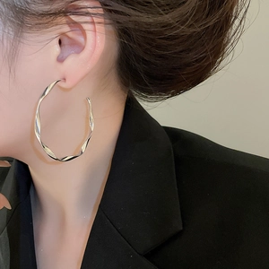 Close-up of a silver twisted hoop earring on a model in a minimalist style