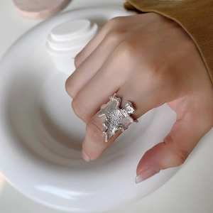 Macro detail of silver irregular wave ring with hammered texture worn on finger