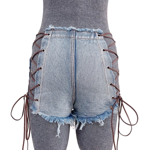 Dettaglio di pantaloncini di denim a vita alta con lacci laterali e bordi sfilacciati