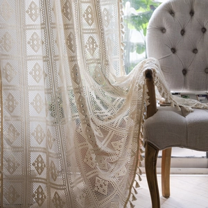 Detailed view of bohemian white lace curtain with delicate hollow patterns and tassels
