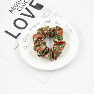 Detail view of a green Christmas scrunchie with white snowflakes on a decorative plate