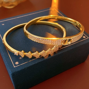 Close-up of gold plated bangles with CZ stones and CD buckle on a blue jewelry box